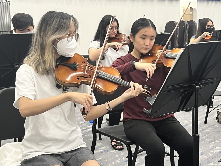 Emma Chen (left), We Have All Music (WHAM) member and senior and Hilary Yang (right), WHAM member and freshman, practice violin at their practice on Aug. 28, 2022. The student-run orchestra practiced to prepare for their performance at the Palladium which will take place on Sept. 28, 2022.