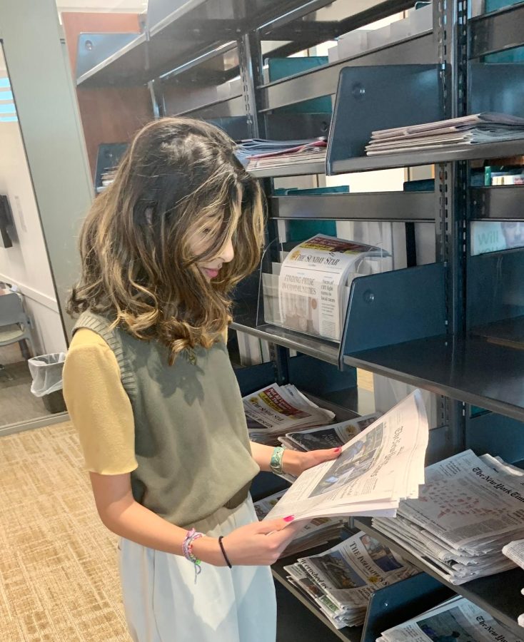Sophomore Sophie Tahir reads the newspaper at the Carmel Clay Public Library. She said news from social media is designed to be catered to individual interests, which is advantageous compared to newspapers.