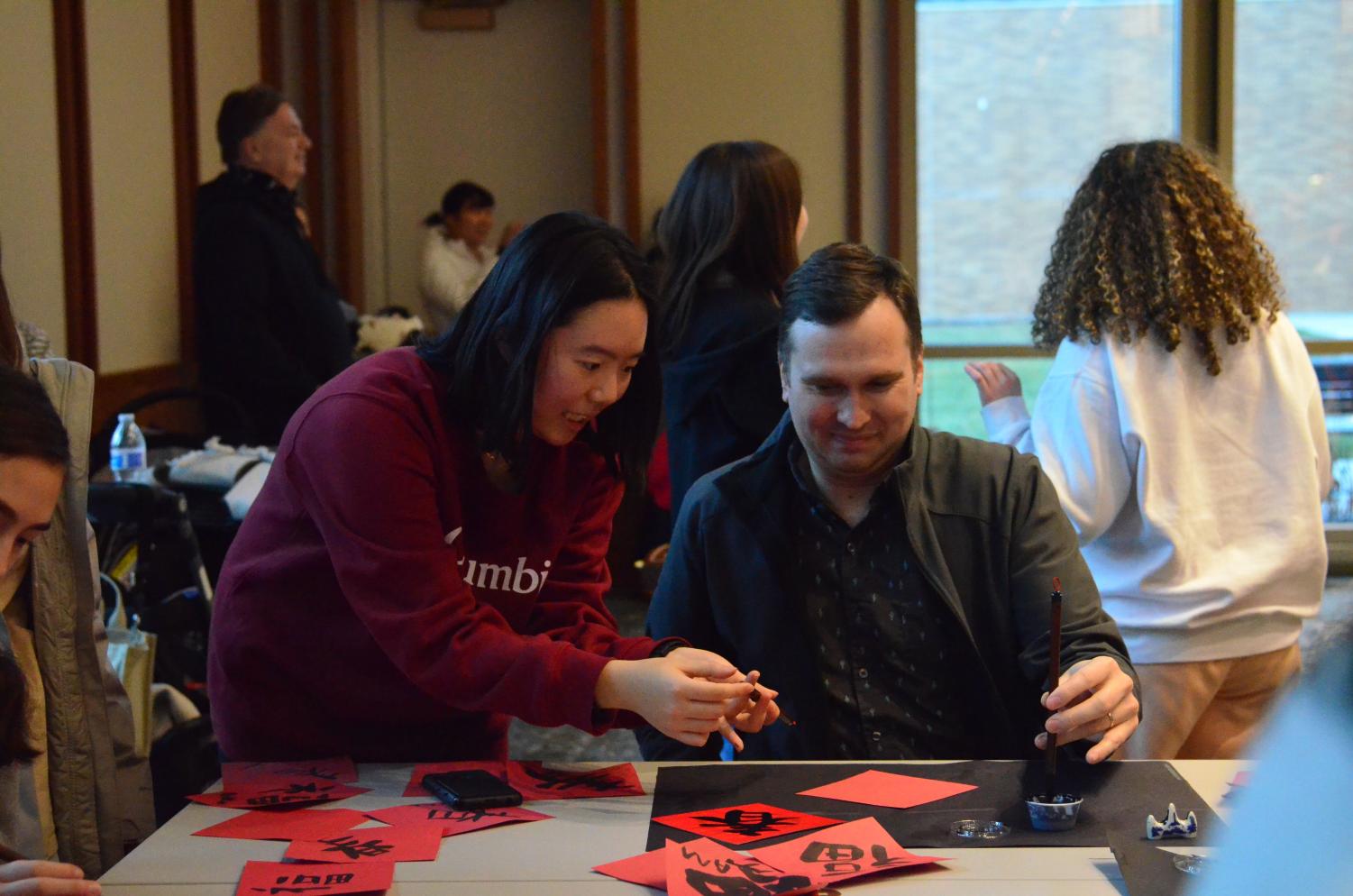 Yuan Heidi Yue, National Chinese Honor Society (NCHS) member and junior, teaches a community member Chinese calligraphy. NCHS organized a Chinese New Year celebration on Jan. 23 at the Carmel Clay Public Library. 