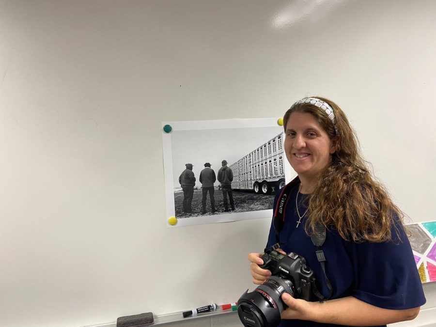 Teacher Laura Moore stands with one of her photos and a camera. She said she gets inspirations from the other art she sees and books she reads.