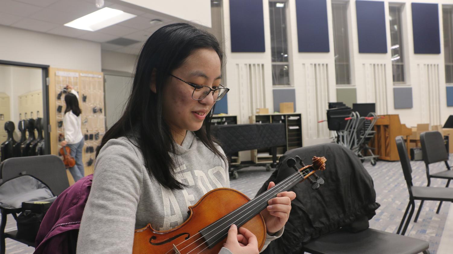 Rachel Wu, member of Symphony Orchestra and senior, studies her music sheet and practices her fingering before after-school rehearsal. According to Wu, “It helps to look through the piece before we start playing together.”
