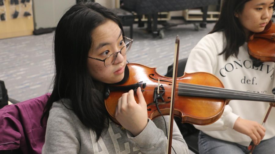 Rachel Wu, member of Symphony Orchestra and senior, looks up at her tuner to match her pitch accordingly. According to Wu, they have to get to rehearsal a few minutes early, so they have time to set up, tune and get ready.