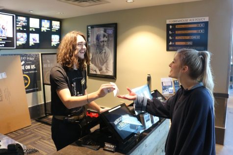 Senior Kyle Sarjent assists a customer in finding a movie on March 4, 2023. Junior Sam Hankins said COVID has affected hiring by reducing the amount of workers that can be on the clock at the same time and we now use more cleaning and sanitation methods like wearing masks and gloves.”