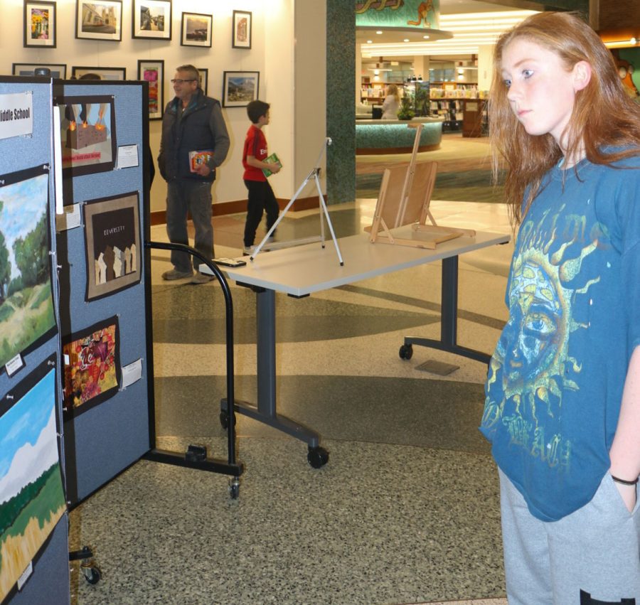 Senior Anya Moffatt looks at the displayed artwork at the CCPL. Moffatt said she enjoys having her art presented to the public. 