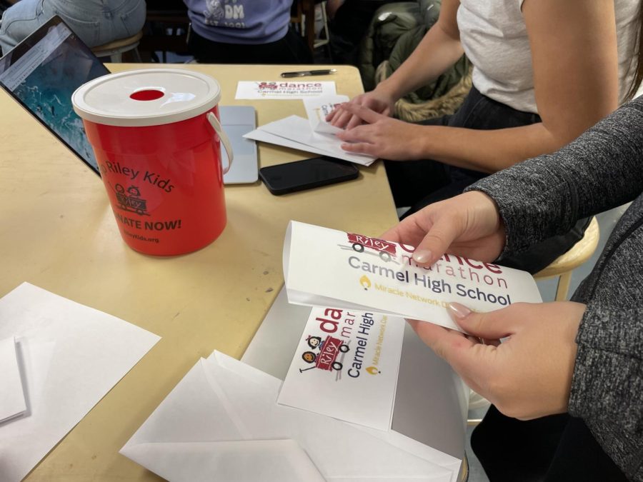As part of a final push for fundraising, senior and Cabinet member Lily Getchell folds a Carmel Dance Marathon flier on Feb. 16, which she will mail in an envelope. Earlier that day, Getchell and other Cabinet members went to classrooms with their signature red buckets to collect spare change for the Riley Hospital for Children. 