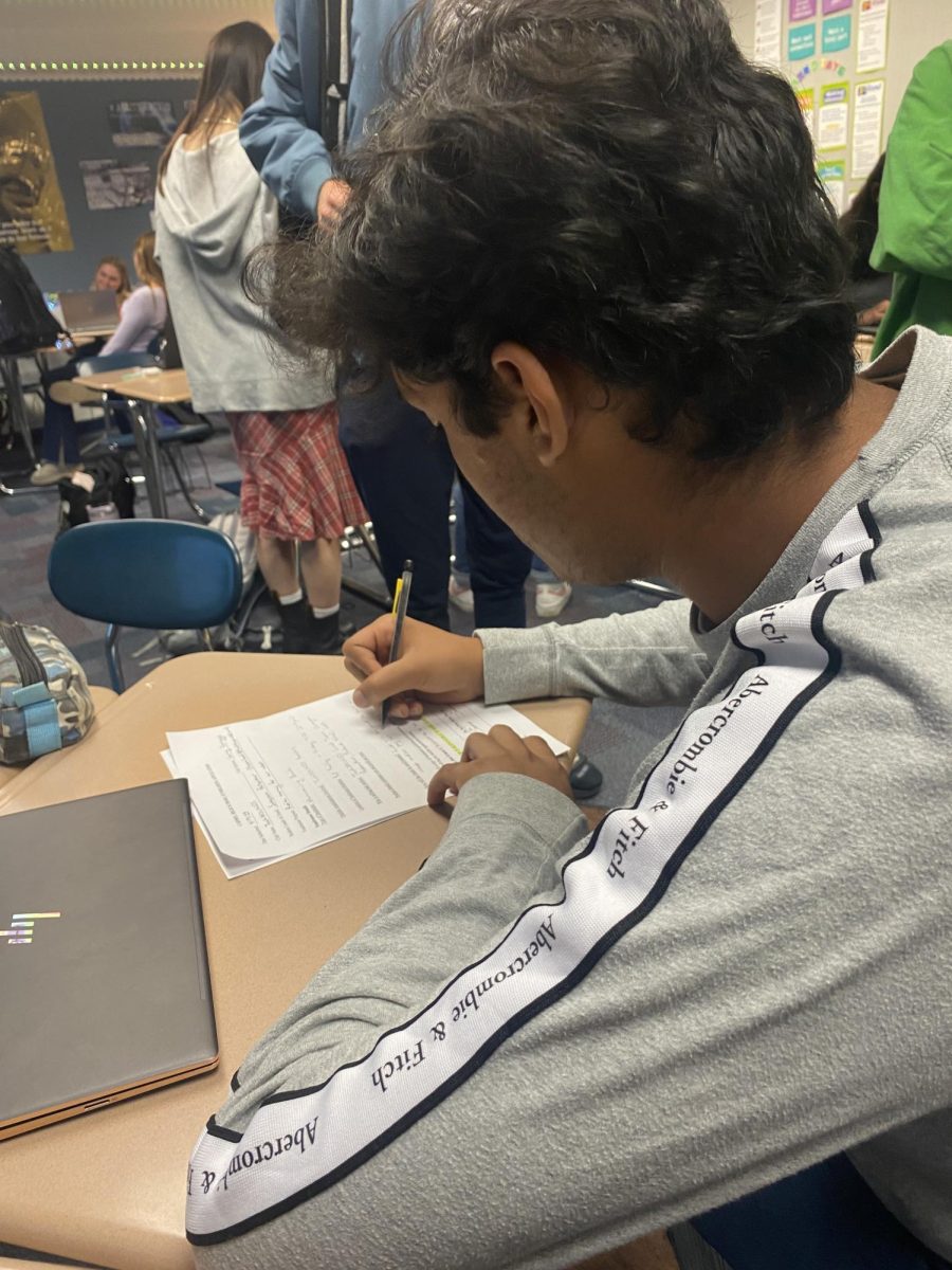 Swayam Patankar, Key Club member and junior, fills out the Key Club code of conduct form. Patankar said that his favorite part about Key Club is giving back to the community  
