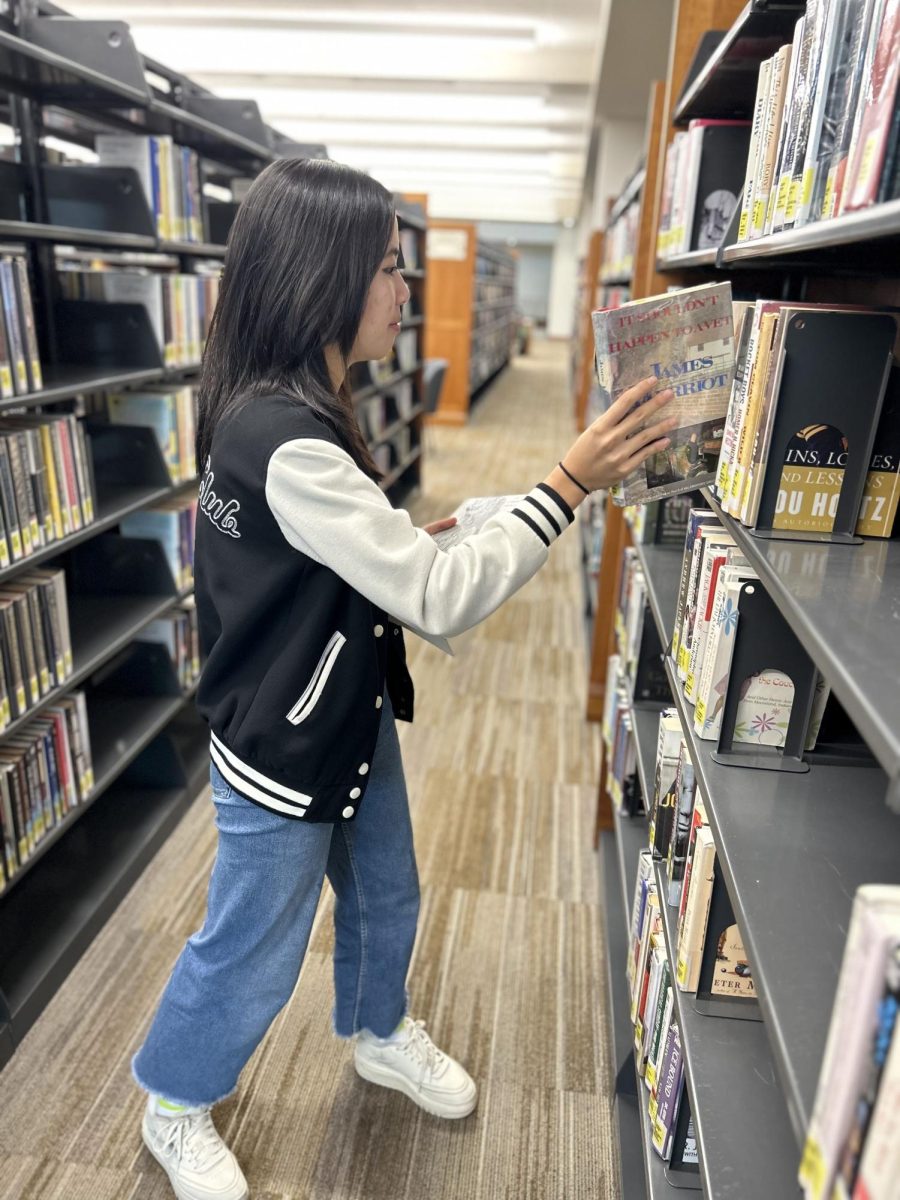 Junior Ava Luo puts books back on shelf at the Carmel Clay Public Library. She said local volunteering brings the community together.
