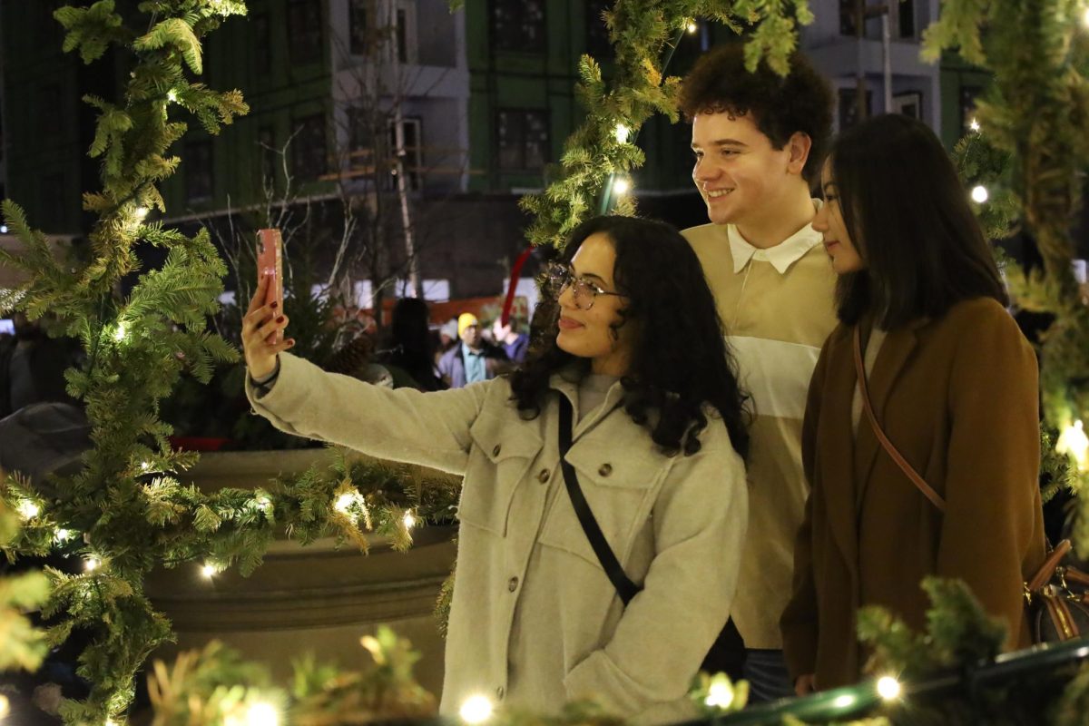 A group take a selfie in one of the tree light arches at the Christkindlmarkt on Dec. 9. The market was a great place to take friends and family for a festive outing and aesthetic pictures. 