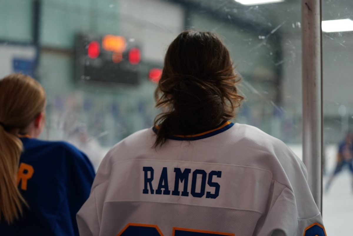 Sophie Ramos, Carmel women’s Icehounds player and junior, watches a hockey match through the glass. When asked about peoples reaction to her playing hockey, Ramos said, Sometimes people are just like ‘Oh I wouldn’t expect that from you’ or they’ll say ‘I didn’t know women’s hockey was a thing.