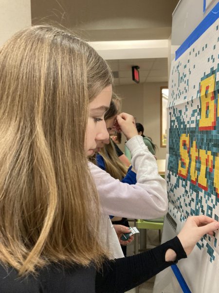 Lily Flint, Best Buddies member and freshman, places stickers on a paint-by-sticker poster on March 15. (My favorite part of Best Buddies is) making new friends and getting to go to all of the activities and events.”