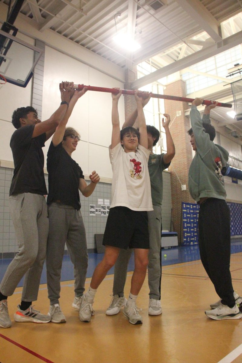 Sophomore Dylan Heagy and his friends lift up the pole after a victorious match against his opposing friends. The club gathered for a lively evening of games, where members showed off their pickleball skills.