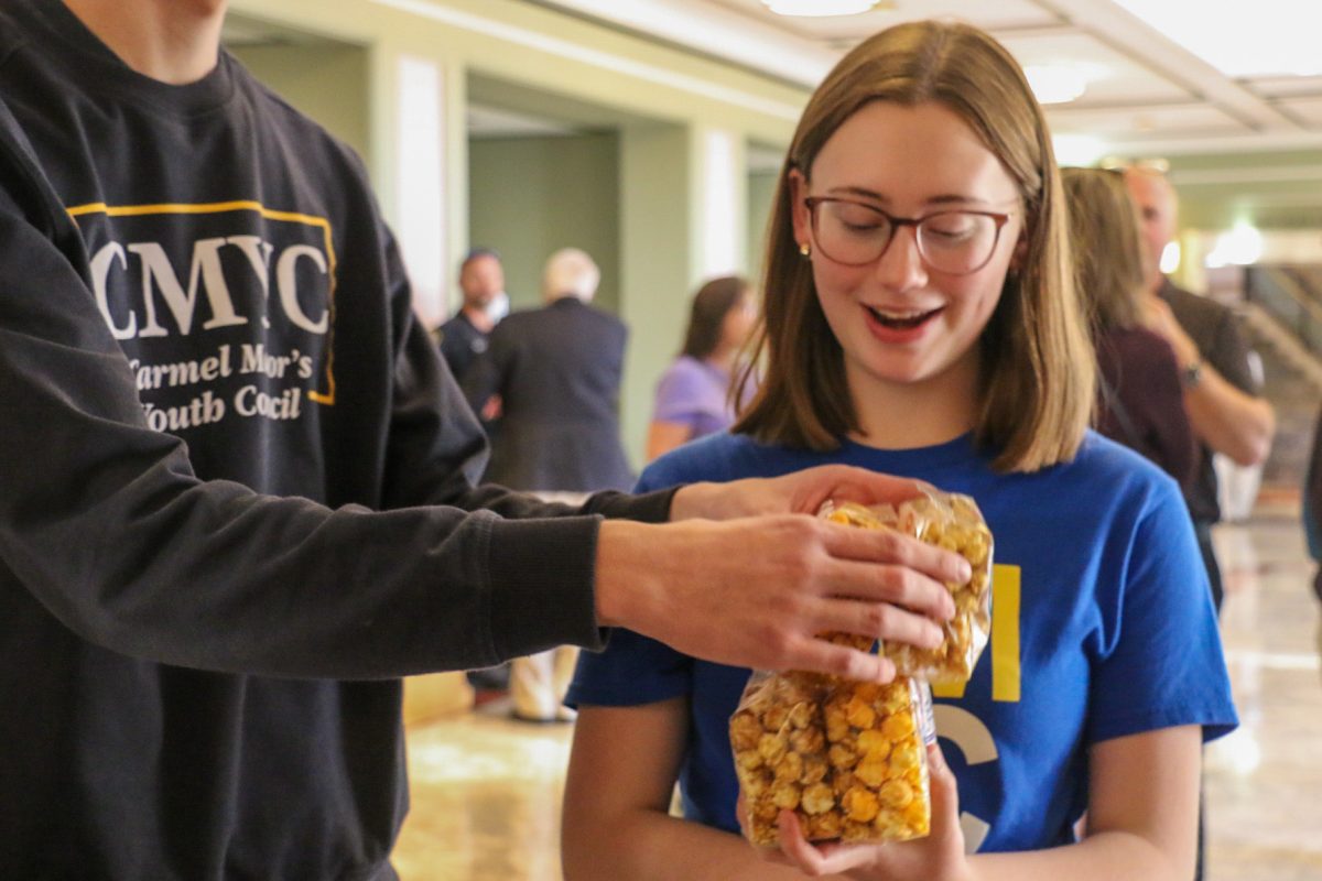 Lilah Walsh, junior and Carmel Mayor’s Youth Council (CMYC) member, holds a stack of popcorn at the State of the City event at the Palladium on Oct. 29. CMYC handed out free popcorn to attendees after the presentations concluded. 