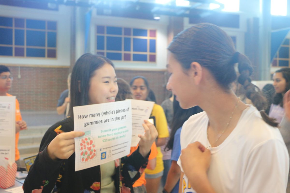 Junior Allison Shen challenges freshmen to solve a math problem for a chance at free candy at the Freshmen Activities Fair during SSRT on August 22 in the Freshmen Cafeteria. Shen had been walking around the cafeteria and posing this challenge to many freshmen in hopes of increasing the membership of Math Club and standing out among other stands by actively seeking out members. Submitted by Shawn Feng