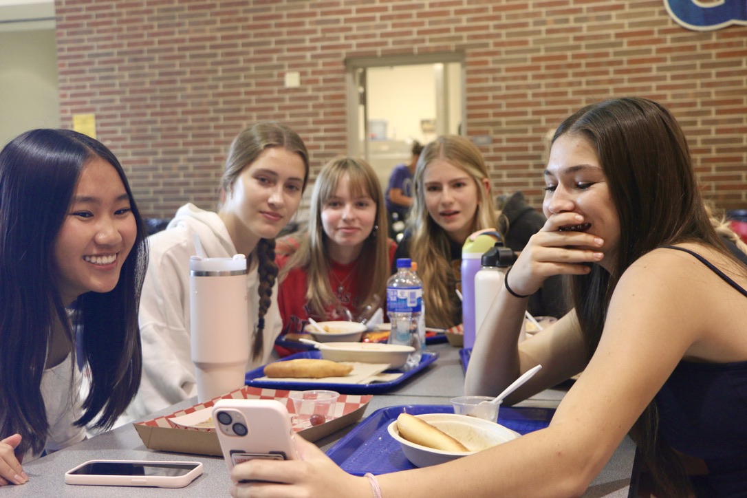 Junior Karen Sun watches a TikTok with her friends during lunch. Sun said she and friends often talk about social media trends and online shopping during their conversations. 
