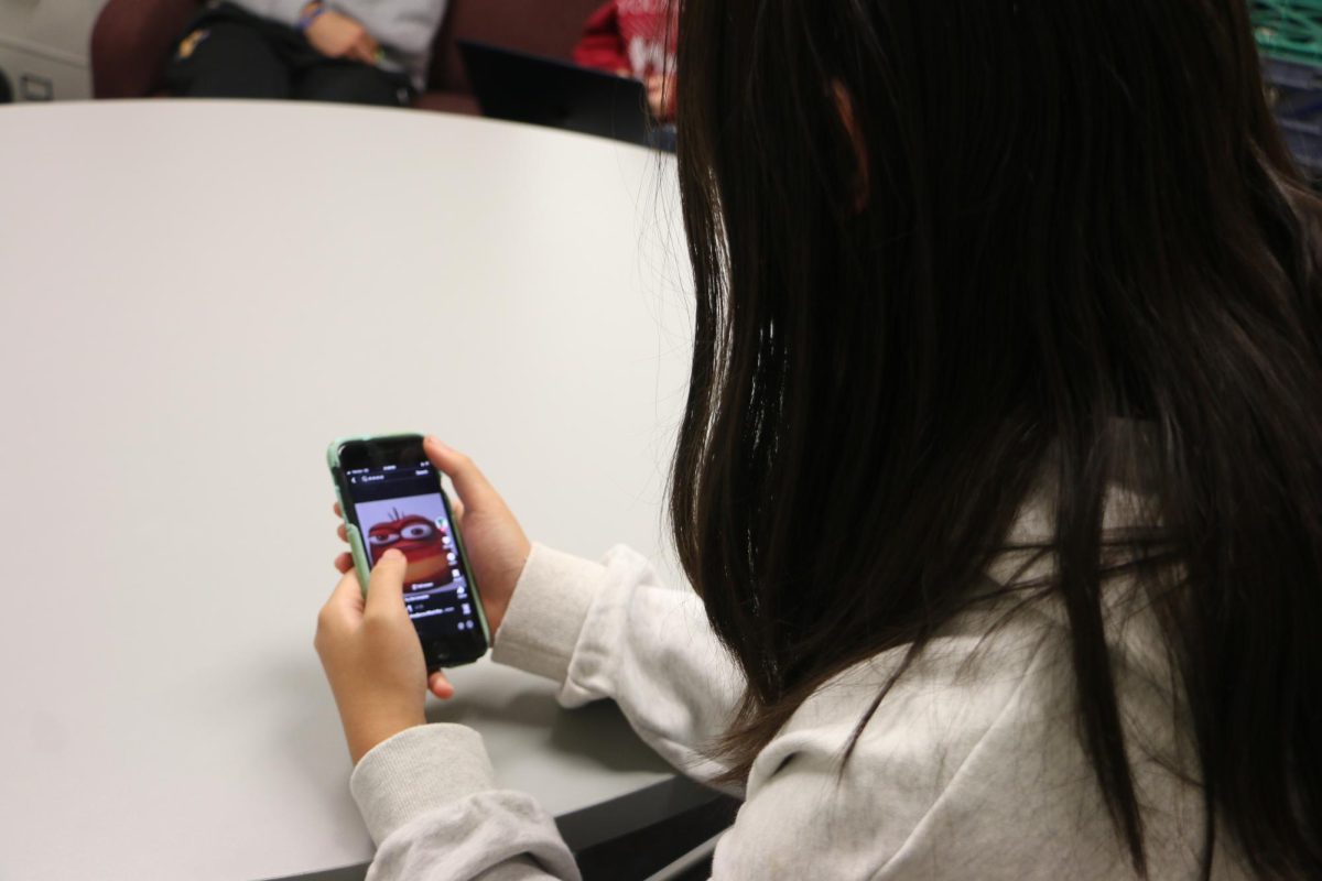 Senior Lala Xiong scrolls on her phone. Xiong said "I don’t think schools can do much to limit social media usage. Even if they ban phones or social media, that doesn’t mean kids won’t still be addicted at home."