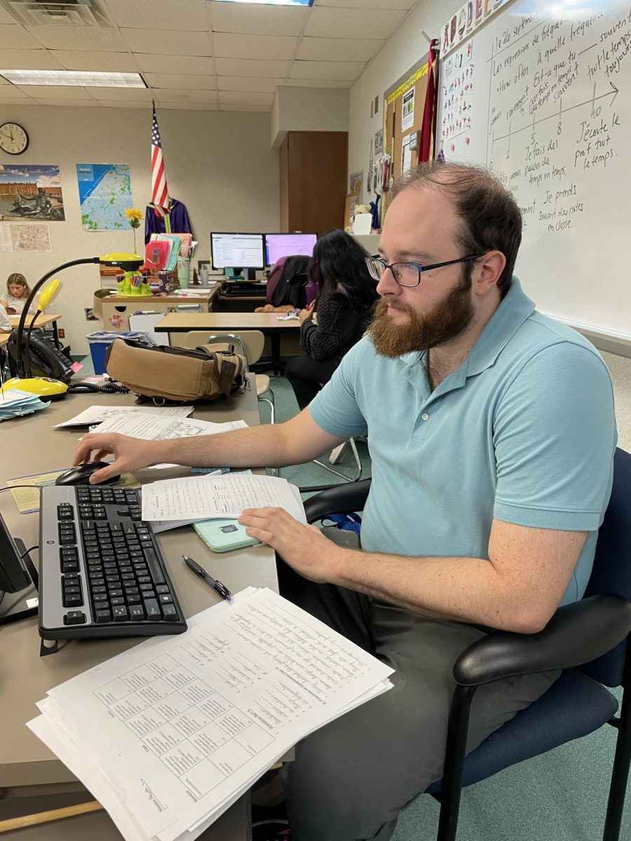 Quiz Bowl sponsor Matthew Cinkoske sits at his desk reviewing student worksheets. Cinkoske said that he enjoys watching the students in the club improve as they go on.
