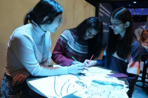 Seniors Amna Ahmad, Eesha Singh and Mahira Hafeez color in various Salvador Dali paintings at the Newfields Lume exhibit. The students were a part of the AP Spanish Language field trip to the art museum.