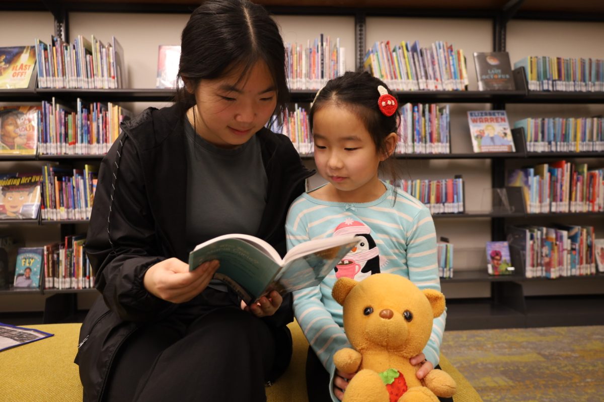 Sophomore Stephanie Tan reads to a young girl at the CCPL after donating toys on Nov. 23. Tan said, “I enjoy being a mentor to kids because I feel like having someone to teach you things and guide you is important.” 