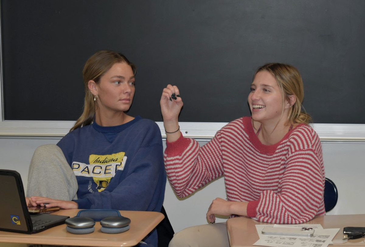 Seniors Maddie McElwee (left) and Rosie Martin (right) respond to a question using sign language during their American Sign Language class period on the afternoon of Nov. 26, 2024. Martin said part of what she loves about ASL is being able to communicate with her friends in a unique way. “I like being able to talk with my friends and have nobody else know what we’re saying,” Martin said.