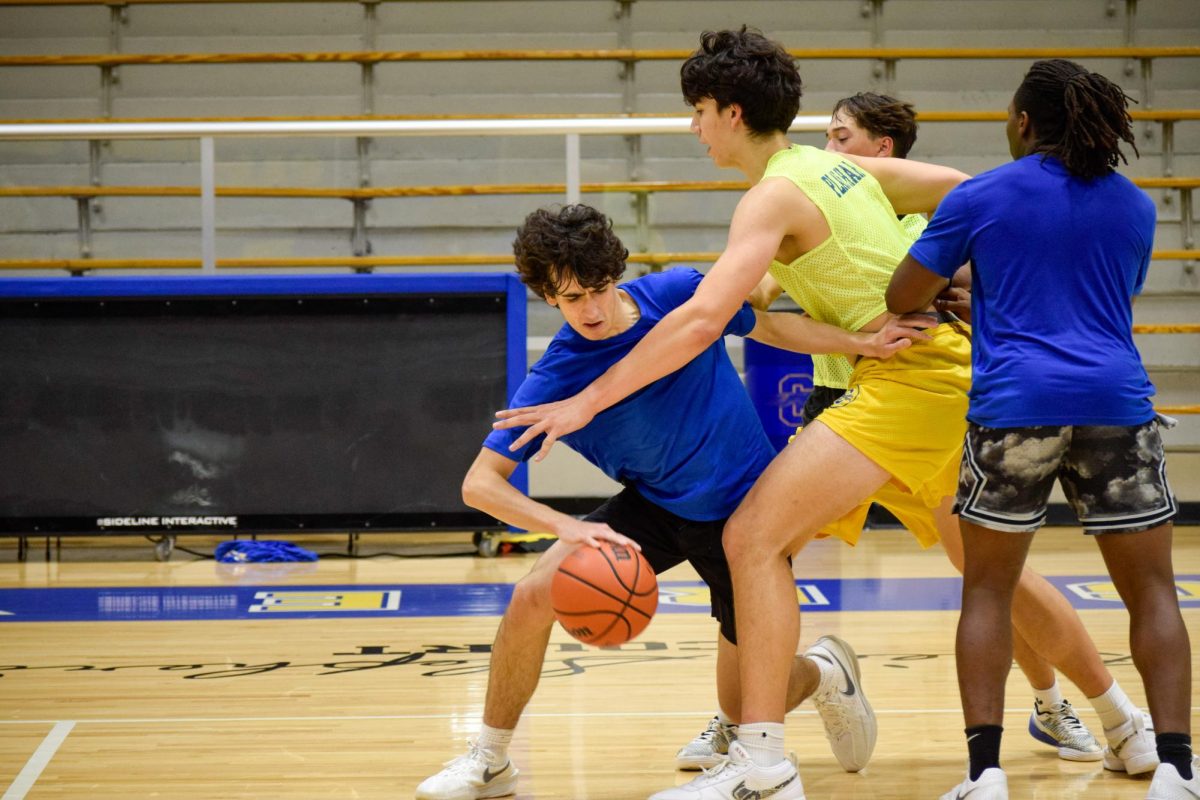 Junior Vincent Nover protects the basketball from the defending team while trying to move around a player on Oct.30. This year’s varsity basketball season consists of ten home games and ten away games. 