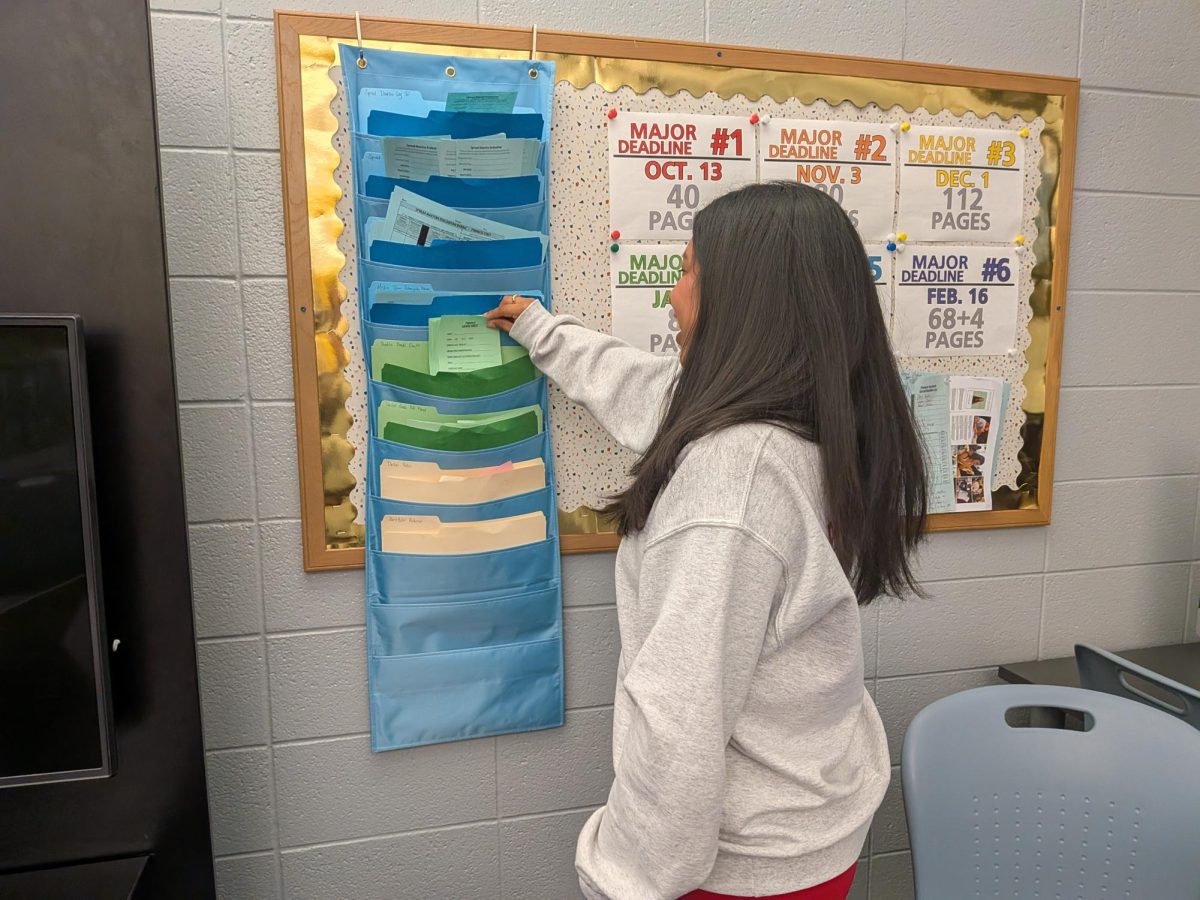 Senior Sara Keating grabs a form for creating a profile. She said, “After we’re done doing interviews for the supplement and the book, we have little assignments that we still have to do, like a profile.”