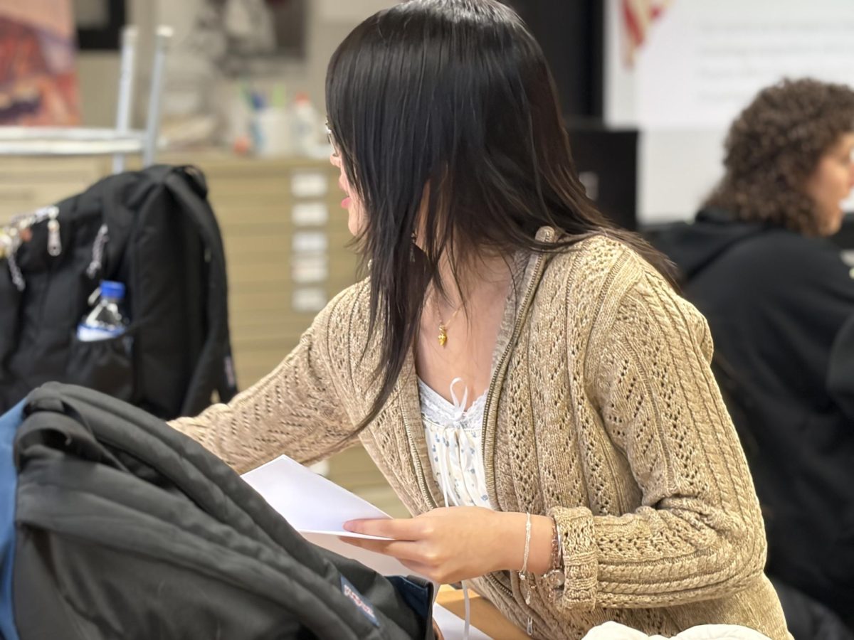 Angela Li, club officer and senior, passes out materials for an activity on March 10. The club members worked on a still-life fruit drawing using different art mediums. Li said, “The wide variety of different styles our members chose to utilize made each piece interesting despite all of them being fruit.”