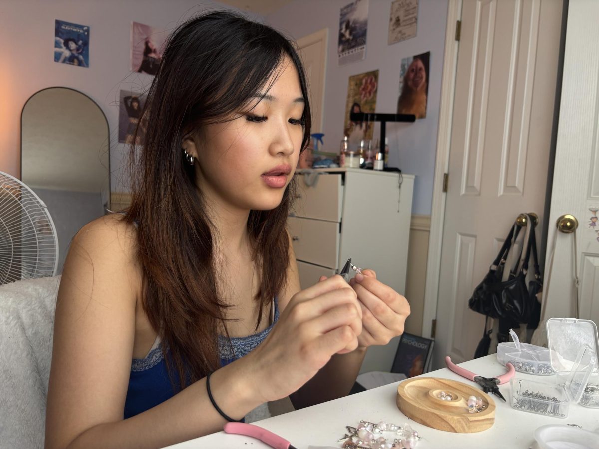 Junior Aleta Lu works on a bracelet inspired by Lucy Bedroque’s album, Fete de la Vanille, for her business, Aleta Bead. She said she uses Instagram as a platform to display and promote her work. She said, “Making bracelets is a good way to make money from doing something I’m passionate about.”